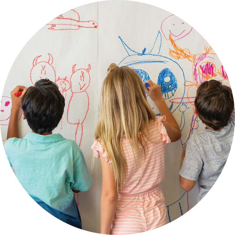 Kids drawing colorful art on a large paper mural at an indoor activity center